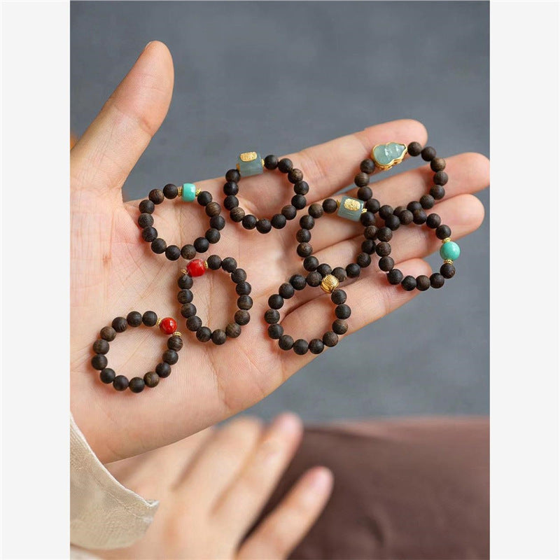 Agarwood Ring – collection of assorted wood bead rings displayed on open palm, spiritual jewelry set