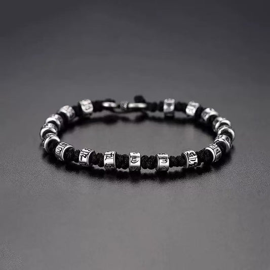 Zen Mantra Cord Bracelet – silver engraved mantra beads on black braided cord with S-hook clasp, dark gray background, mindfulness jewelry