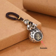 Rotating coin money pouch keychain demonstrating rotatable feature with arrow indicator on brown background