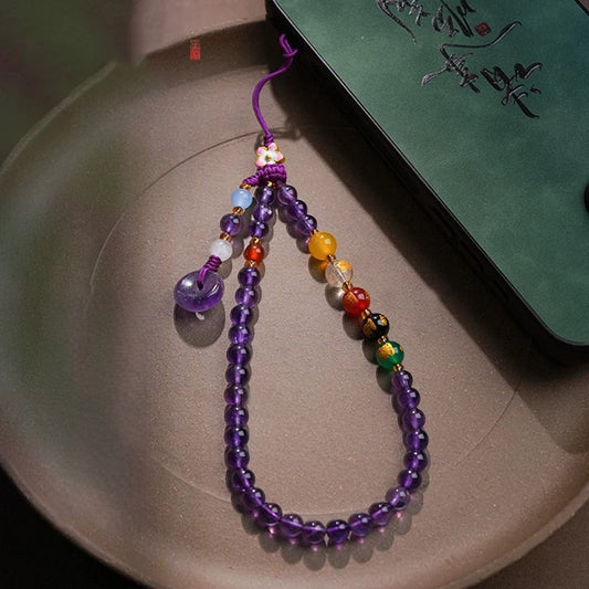 Amethyst Phone Charm – laid on ceramic plate with green book, elegant display
