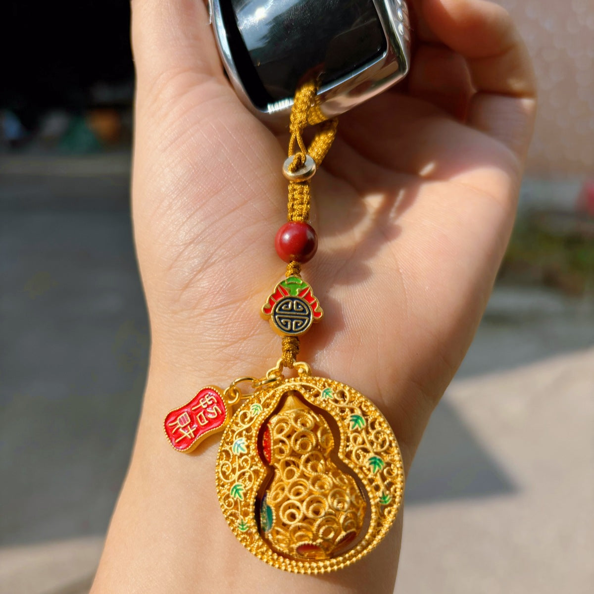 Gold enamel calabash keychain trio with fortune and peace plaques on red background