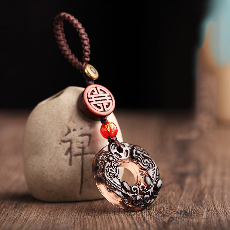 Pixiu Obsidian Keychain – pixiu disc leaning against engraved zen stone with warm lighting, spiritual keychain