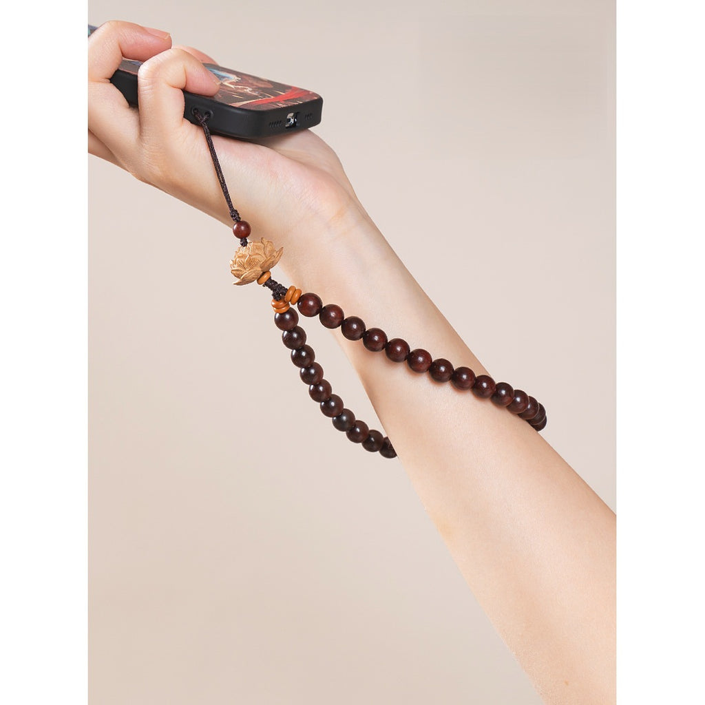 Zodiac Wood Bead Lanyard – Hand holding phone with deep red sandalwood lotus lanyard on arm, warm tone lifestyle shot
