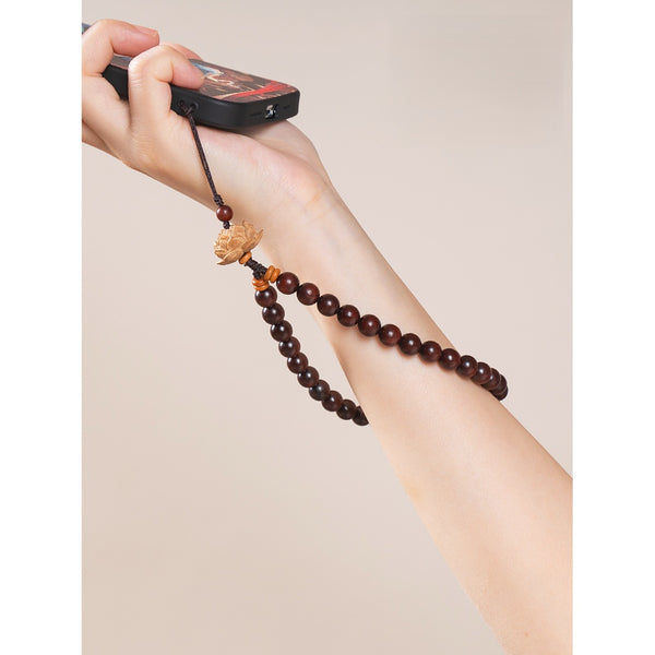Zodiac Wood Bead Lanyard – Hand holding phone with deep red sandalwood lotus lanyard on arm, warm tone lifestyle shot