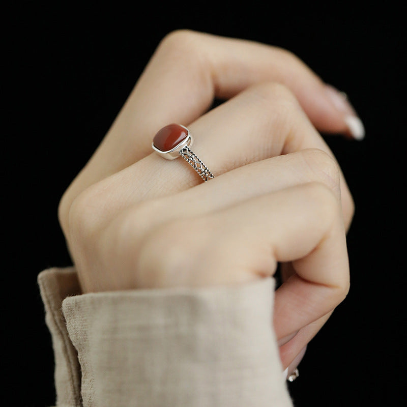 Red Agate Openwork Ring – on hand with black background and natural linen sleeve cuff, silver openwork ring