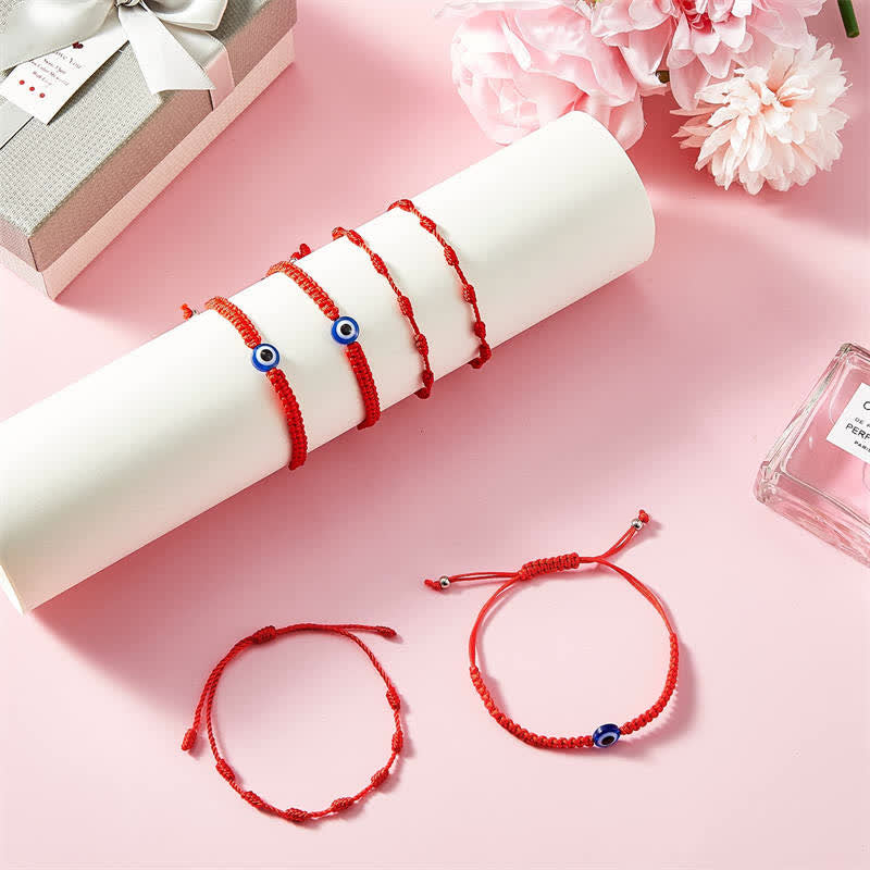 4Pcs Evil Eye Red String – Red cord bracelets on white display with gift box and flowers, pink background