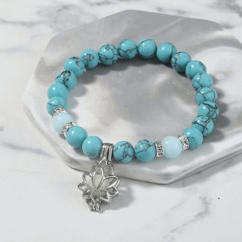 Tibetan Turquoise Glowstone Lotus Bracelet – turquoise stone beads with silver lotus charm on gray ceramic dish, lotus charm bracelet