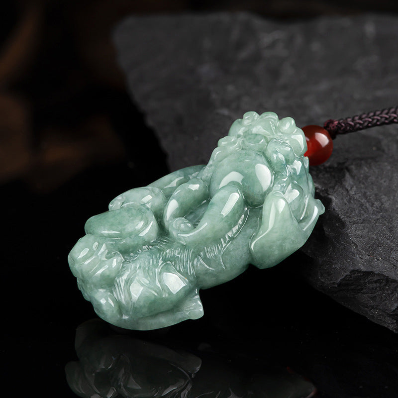 Jade PiXiu Necklace – Jade Pixiu pendant angled on black rock with red bead and cord, feng shui jewelry