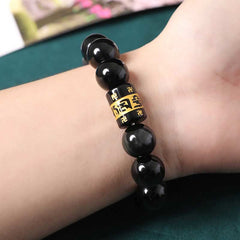 Rainbow Obsidian Bracelet – Worn on wrist showing glossy black beads and gold mantra bead, men's bead bracelet