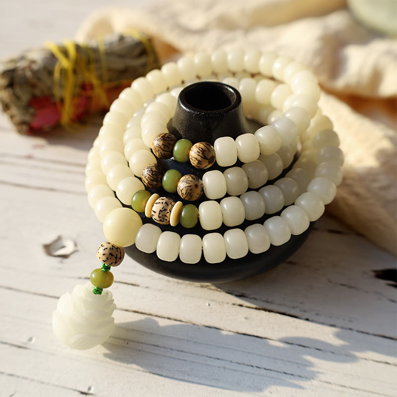 Bodhi Seed Lotus Mala - draped on matte black ceramic vessel, rustic white wood backdrop, mindful living