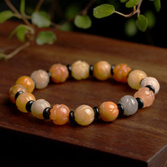 Golden Silk Jade Lotus Bracelet – Carved lotus beads in peach amber tones with black spacers on wood, lotus jade