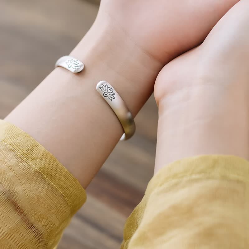 Lotus Cuff Bracelet – Matte silver bangle held by hands showing lotus engravings, healing bracelet