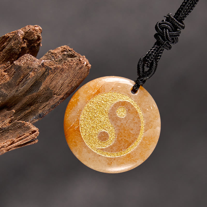 Yin Yang Crystal Necklace – Orange agate round pendant with gold yin-yang engraving, natural marbled patterns on black cord, 