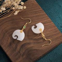 Feng Shui Elephant White Jade Fortune Earrings styled on wood surface