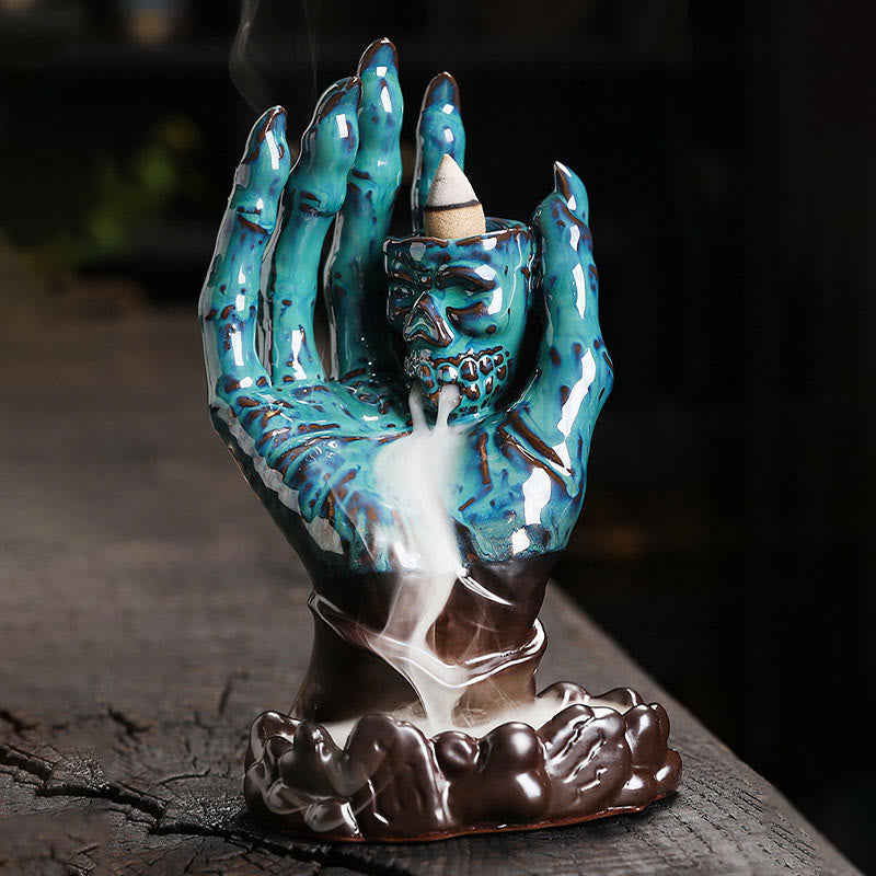 Ceramic Ghost Hand Skull Incense Burner – Teal ceramic hand with skull holder, white smoke waterfall over brown cloud base