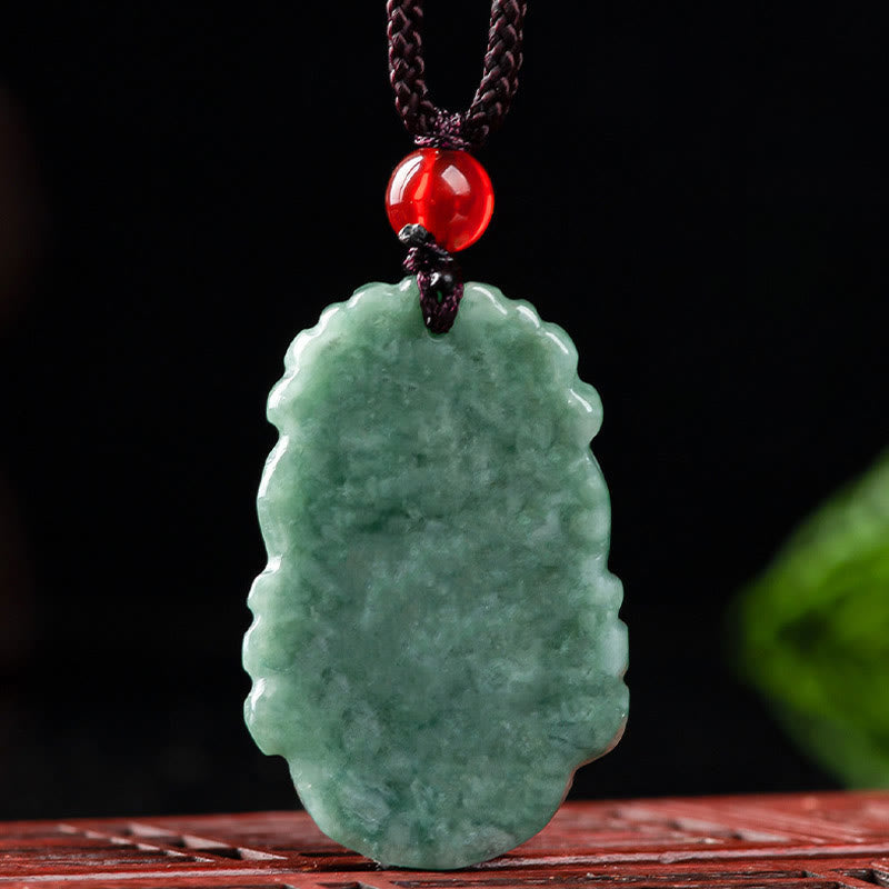 Jade Zodiac Prosperity Necklace – Scalloped jade amulet with red bead on dark wood, elegant