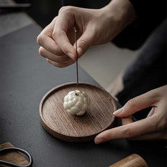 Ceramic Lotus Incense Burner with hand inserting incense stick on wooden tray, mindful