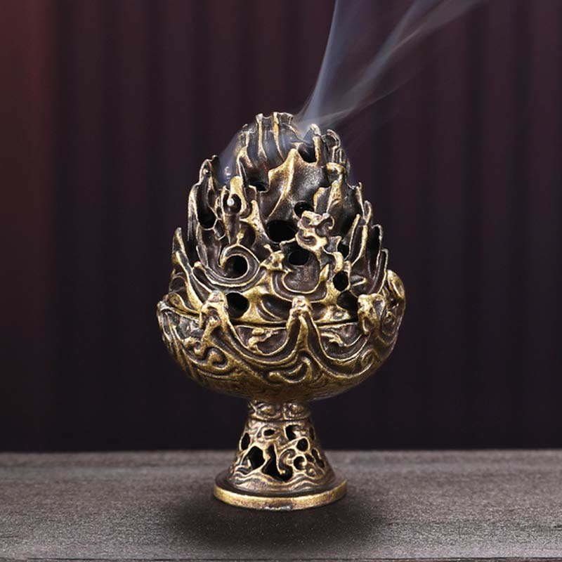Open Bronze Incense Burner – Lid set aside revealing lit cone inside, dark matte surface, warm directional lighting