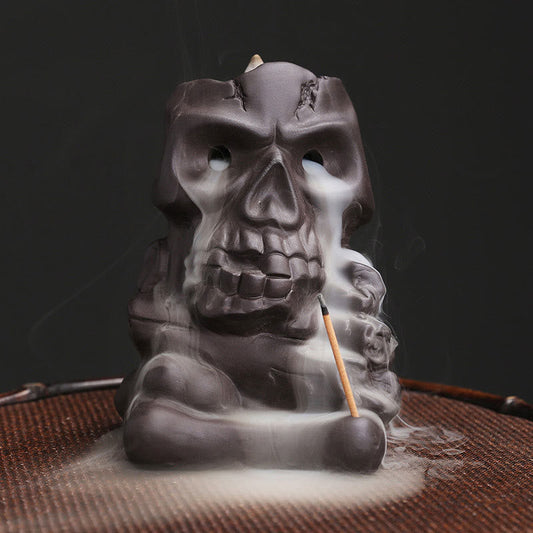 Skull Head Purple Clay Incense Burner – smoke cascading from eye sockets over woven mat, backflow incense