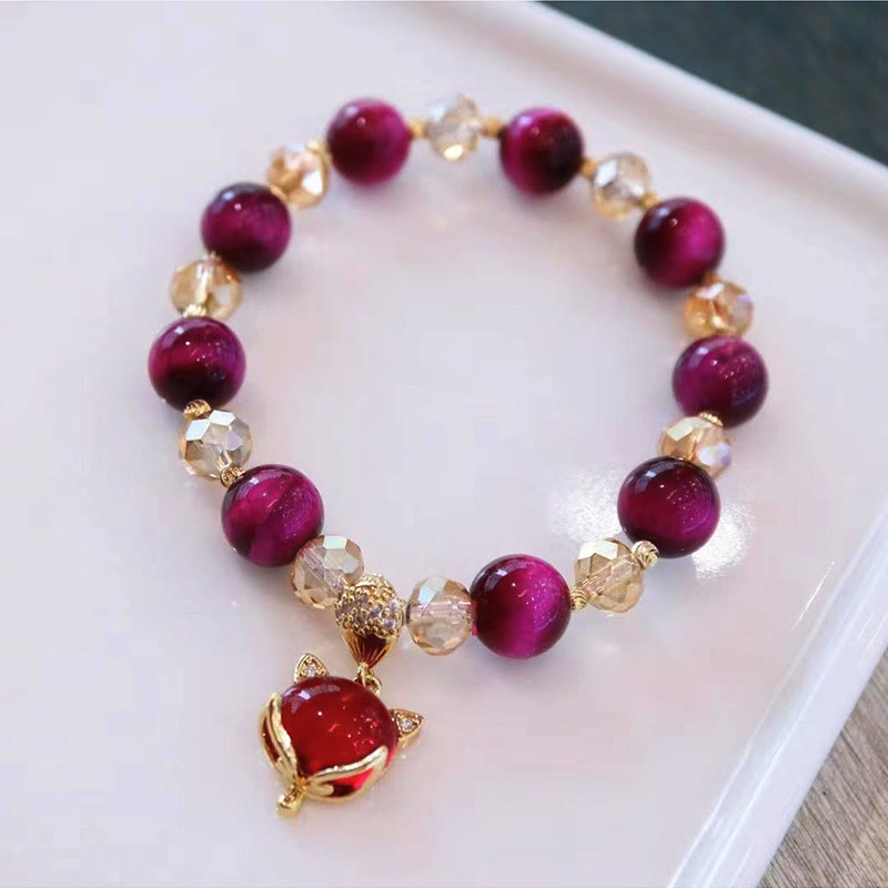 Red Tiger Eye Fox Bracelet – Deep magenta beads with gold fox charm on white tray, balance jewelry