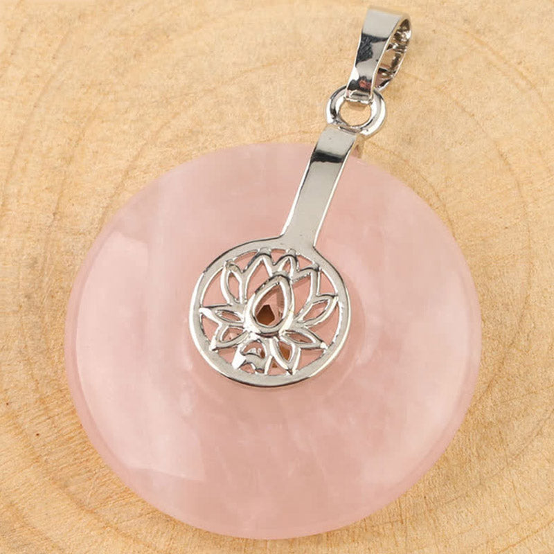 Crystal Amethyst Pink Crystal Lotus Necklace – Rose quartz donut pendant flat lay on wood, lotus metalwork and natural inclusions visible