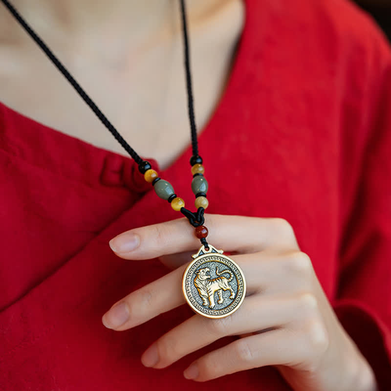 12 Chinese Zodiac Fortune Necklace Pendant – Tiger zodiac pendant necklace worn on red garment, gold and silver two-tone medallion with walking tiger relief, Greek key border, jade and carnelian beaded cord, Chinese New Year cultural jewelry
