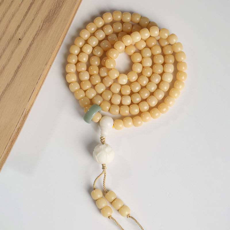 Bodhi Seed Lotus Dzi Bracelet - Coiled flat lay on white with wood edge, green jade ring and lotus tassel