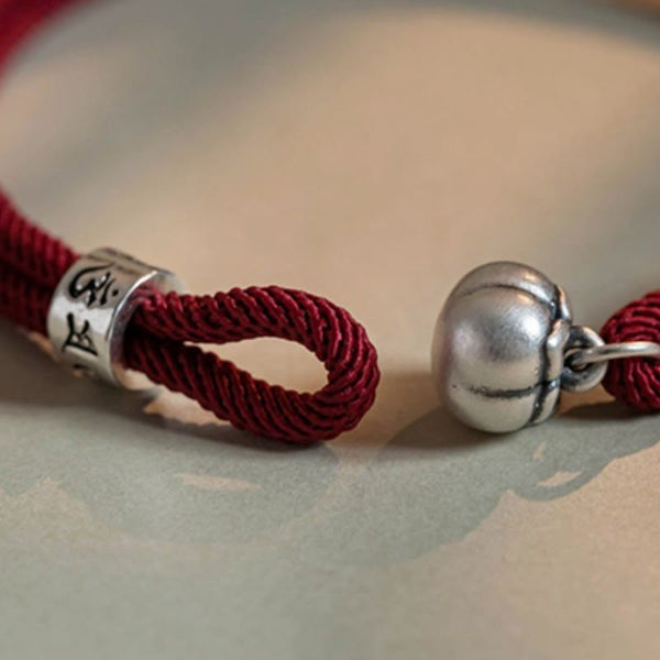 Om Mani Padme Hum Bracelet - Burgundy cord with antiqued silver bell and mantra cylinder on soft background