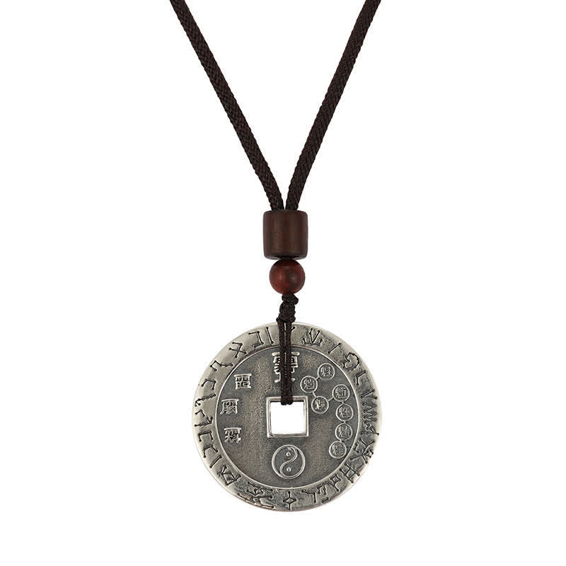 Bagua Yin Yang Obsidian Necklace - engraved silver coin with yin-yang on white background, studio shot