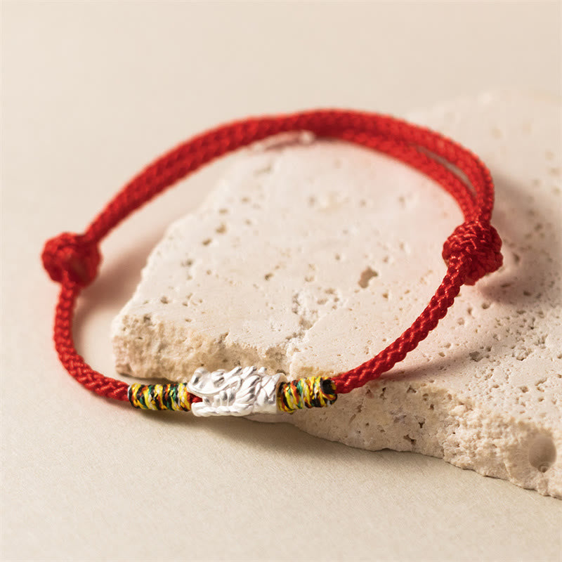 Sterling Silver Dragon Red Rope Bracelet - silver textured bead on red braided cord resting on stone, Style