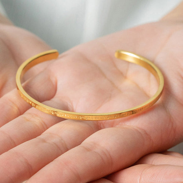 Om Mani Padme Hum Engraved Bracelet – gold cuff resting in open palm showing engraving, gift jewelry
