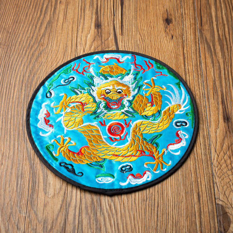 Dragon Embroidery Tea Cup Coaster Mat - turquoise base golden dragon coiled pose, angled overhead on wood, bold accent