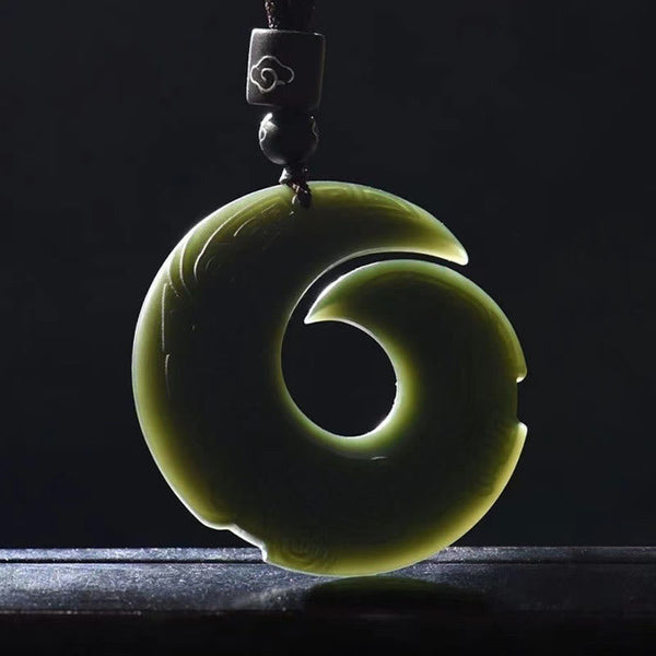 Hetian Cyan Jade Peace Buckle Luck Necklace – Backlit dark olive-green jade pendant showing translucent spiral S-curve form with polished finish