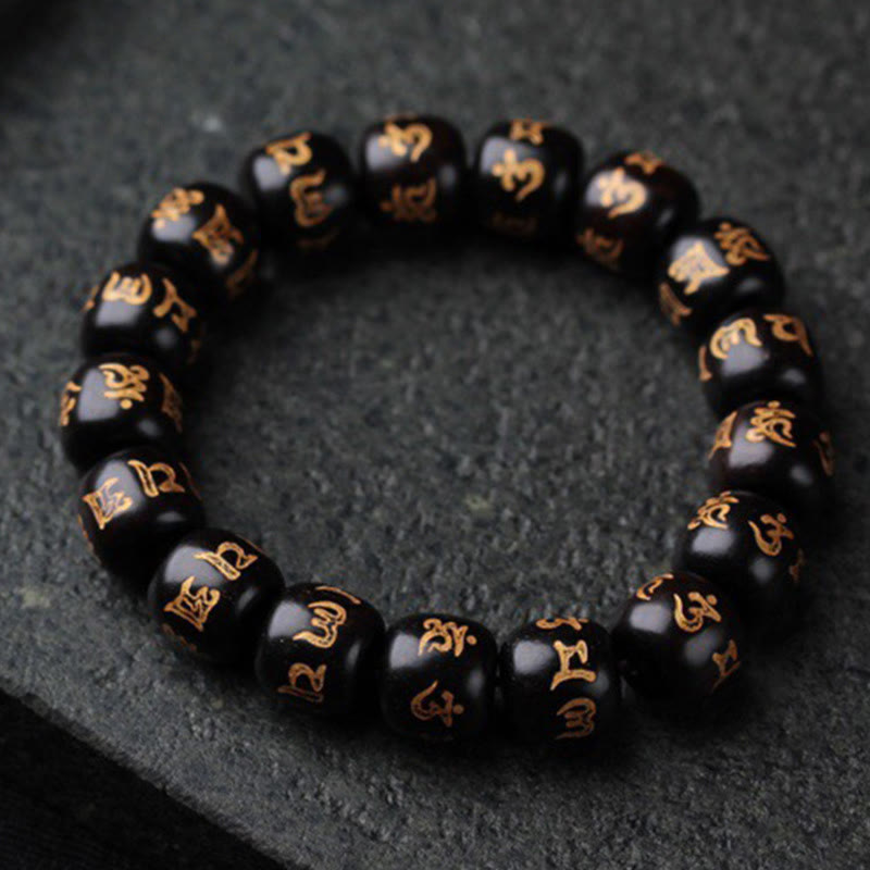 Ebony Wood Om Mani Padme Hum Bracelet – Circular arrangement on dark stone showing gold inscriptions, prayer beads