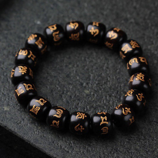 Ebony Wood Om Mani Padme Hum Bracelet – Circular arrangement on dark stone showing gold inscriptions, prayer beads