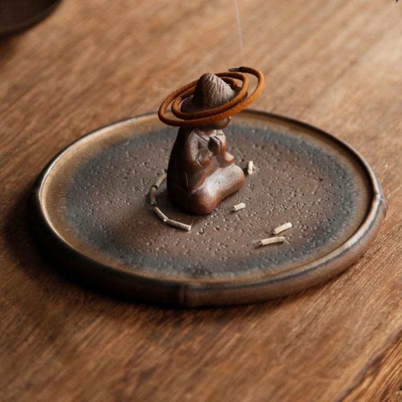 Seated monk figure with burning coil incense halo on wooden surface, mindful