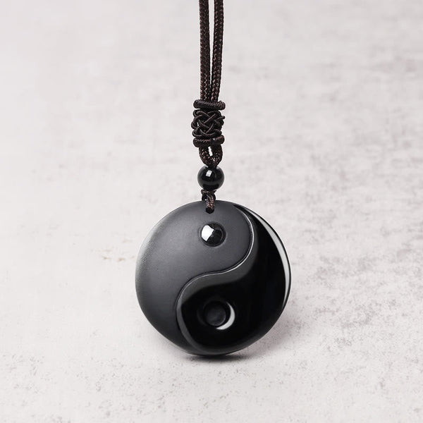 Black Obsidian Nine-Character Mantra Necklace – Yin-Yang obsidian pendant on light background, minimalist jewelry photography