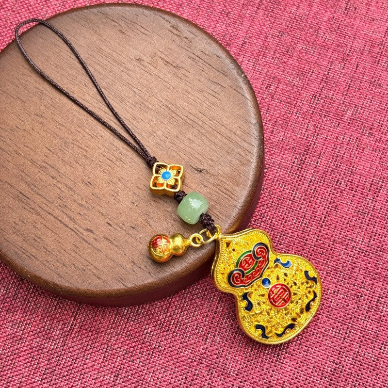 Gold enamel calabash keychain with jade bead and small gourd charm, brown cord close-up