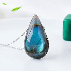 Labradorite water drop pendant necklace with striking blue-green iridescent labradorite teardrop cabochon on delicate silver chain displaying natural color flash against soft green botanical background
