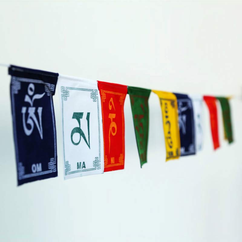 Tibetan Prayer Flags – Side view with depth of field showing mantra flags on white wall, Tibetan blessing banner