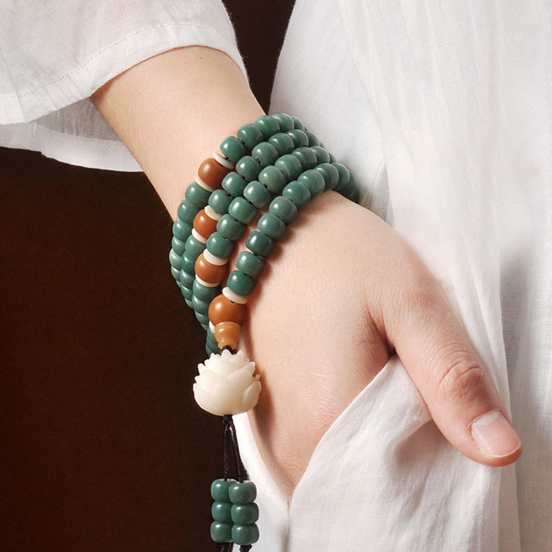 Lotus Cyan Bodhi Seed Bracelet - model wearing multi-strand wrap mala with carved lotus and amber beads, wrist shot