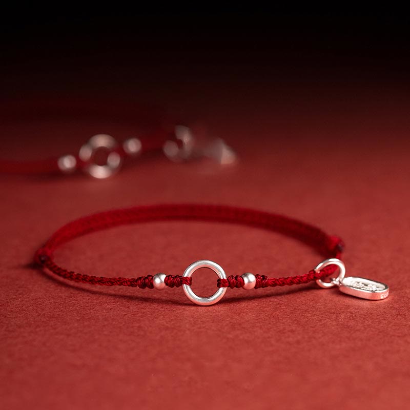 Sterling Silver Lotus Peace Buckle Red String Bracelet – Red braided cord bracelet with sterling silver peace buckle ring, flanking beads, and oval charm on a matching red background