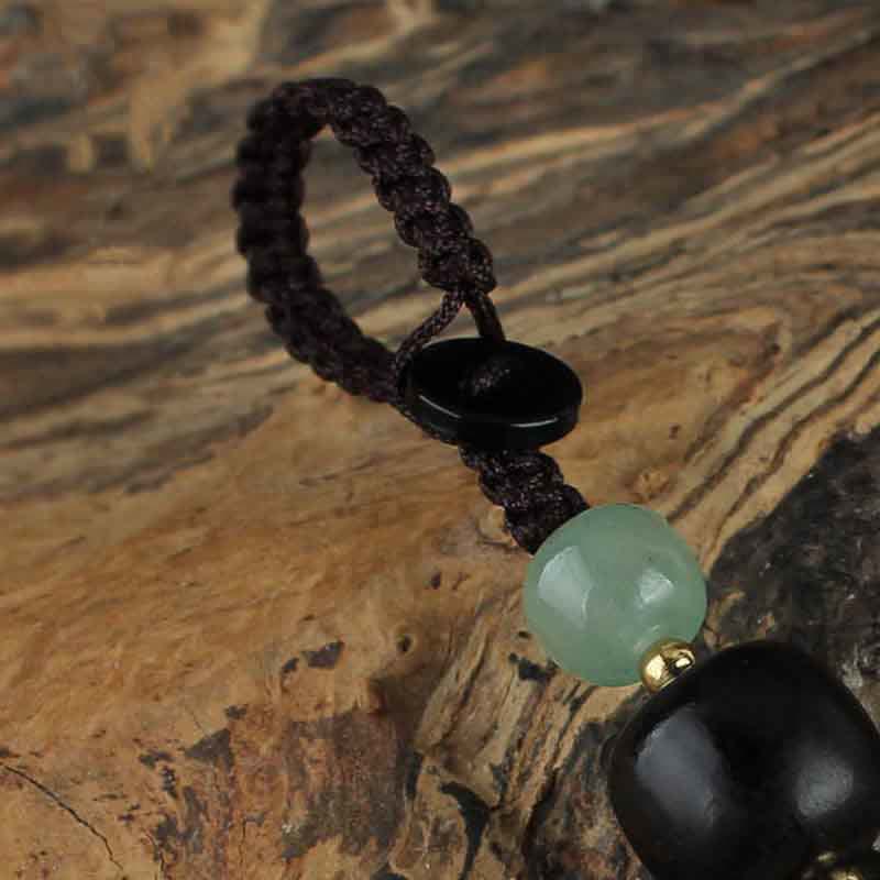 Jade PiXiu Peace Buckle Abundance Key Chain – Close-up carved jade peace buckle disc on dark wood surface, artisan