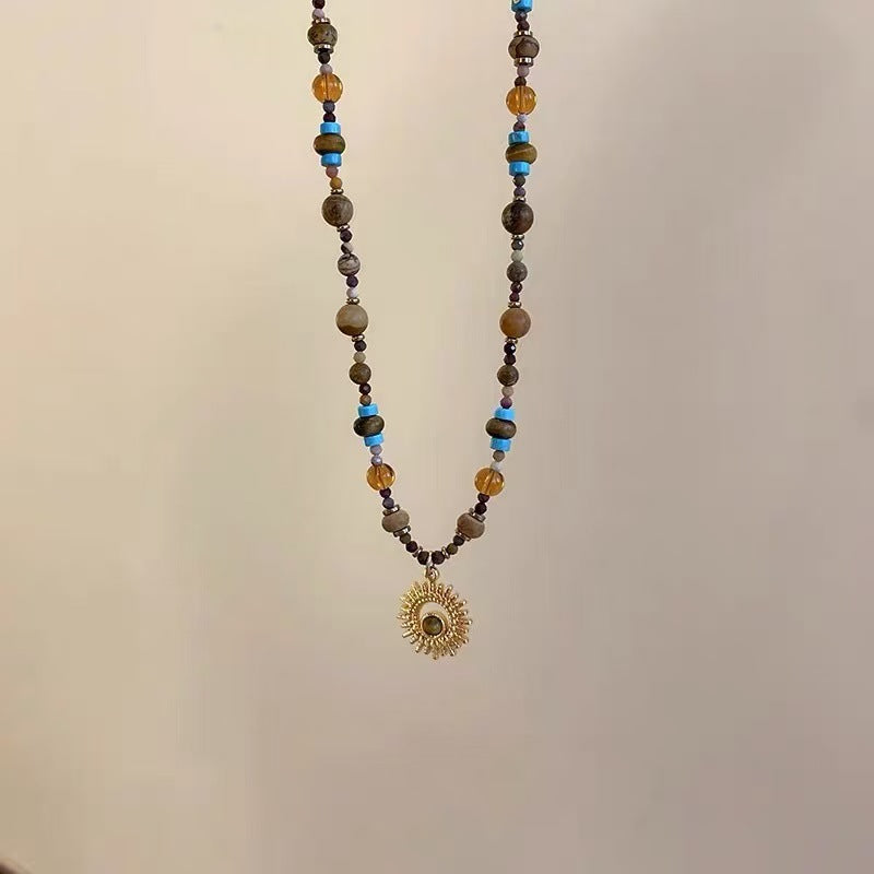Sunflower Necklace – hanging beaded necklace with amber and blue stone beads, gold sunburst pendant, minimalist display