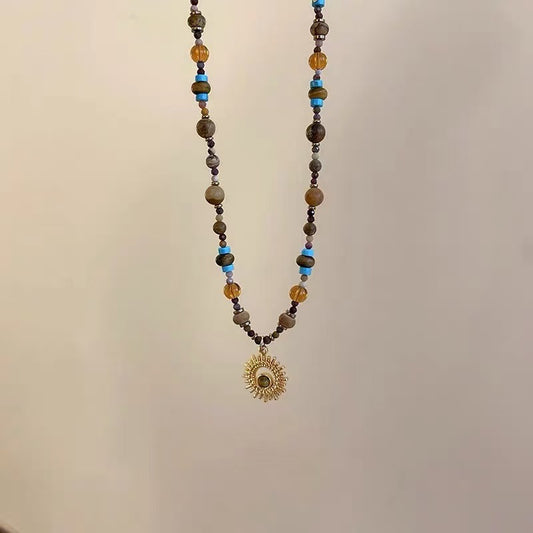 Sunflower Necklace – hanging beaded necklace with amber and blue stone beads, gold sunburst pendant, minimalist display