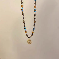 Sunflower Necklace – hanging beaded necklace with amber and blue stone beads, gold sunburst pendant, minimalist display