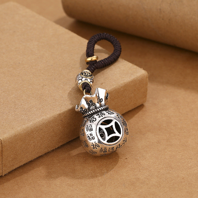 Back view of rotating money pouch keychain showing ancient coin镂空 pattern and Fu blessings on brown background