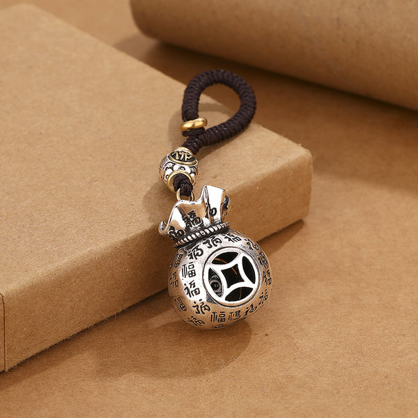Back view of rotating money pouch keychain showing ancient coin镂空 pattern and Fu blessings on brown background