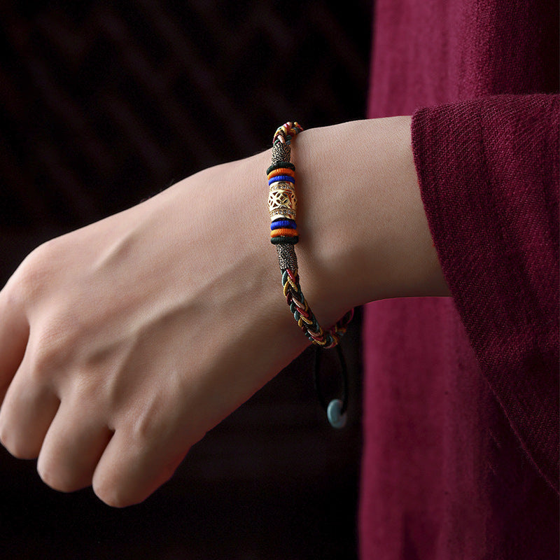 Tibetan Five-Color Bracelet – wrist shot on model in burgundy sleeve, adjustable colorful knot band, spiritual jewelry
