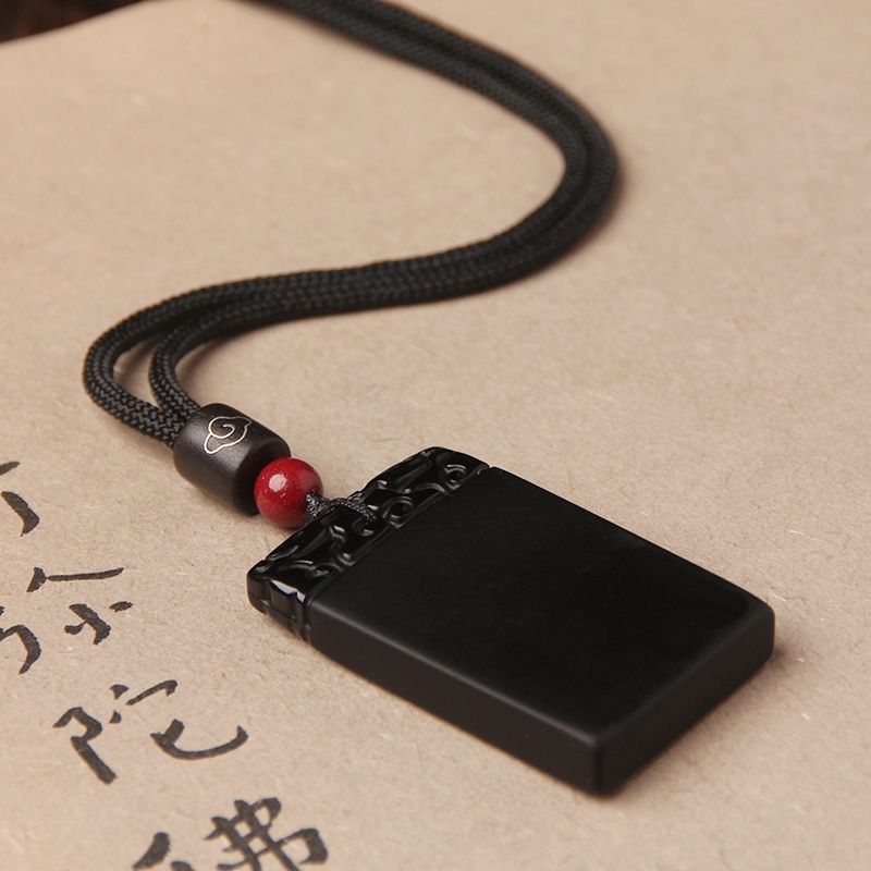 Black Obsidian Pendant – Close-up of black obsidian plaque with red bead on traditional script paper, zen accessory